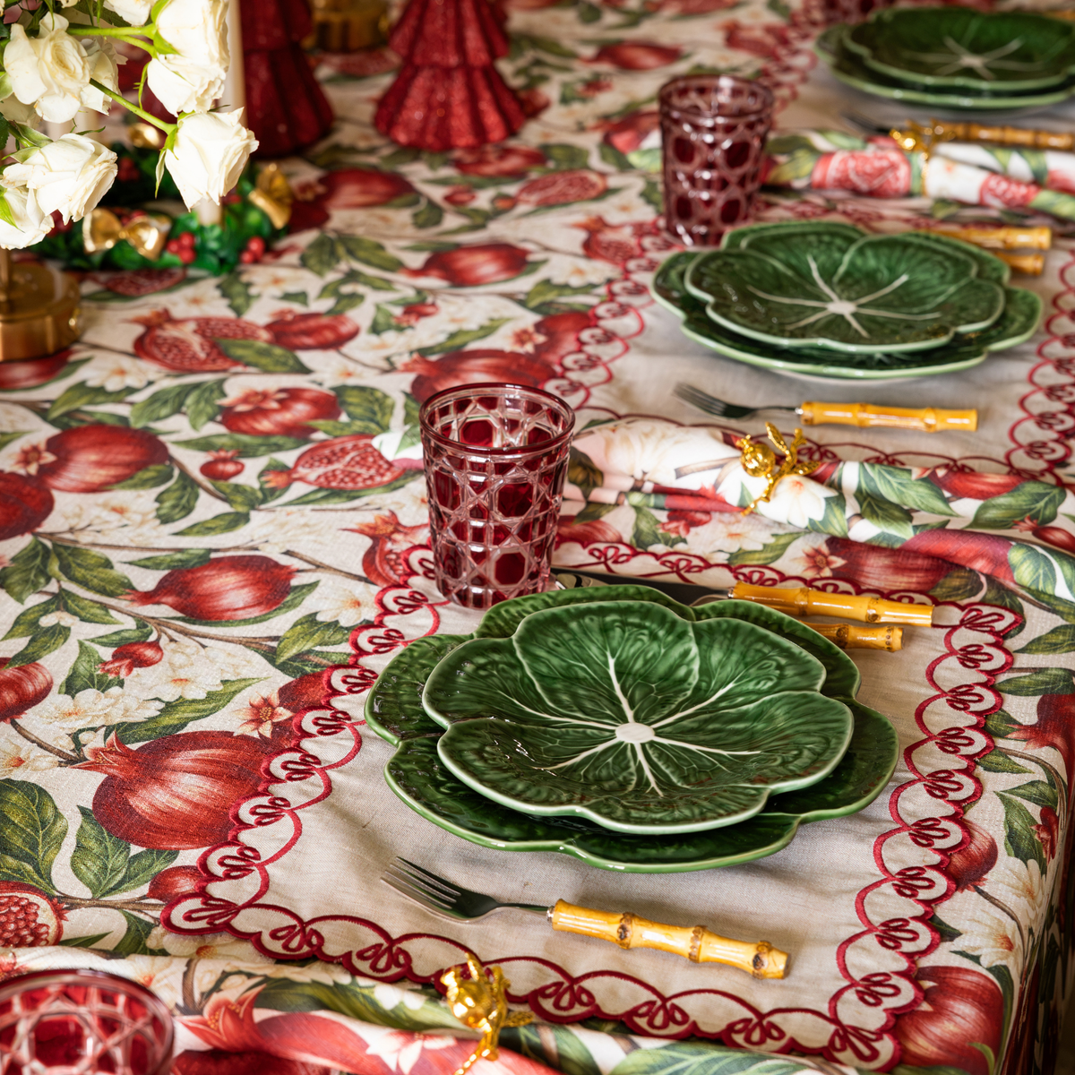 Pomegranate Christmas table styled with green cabbage plates, red geometric glass tumblers and Pomegranate table cloth