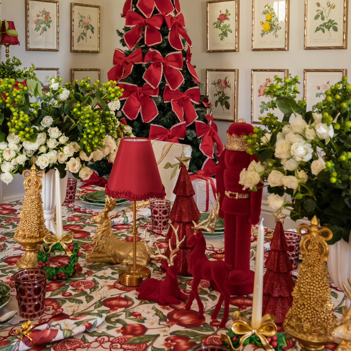 Pomegranate Christmas table styled with burgundy velvet nutcracker, burgundy velvet reindeer and gold Christmas tree