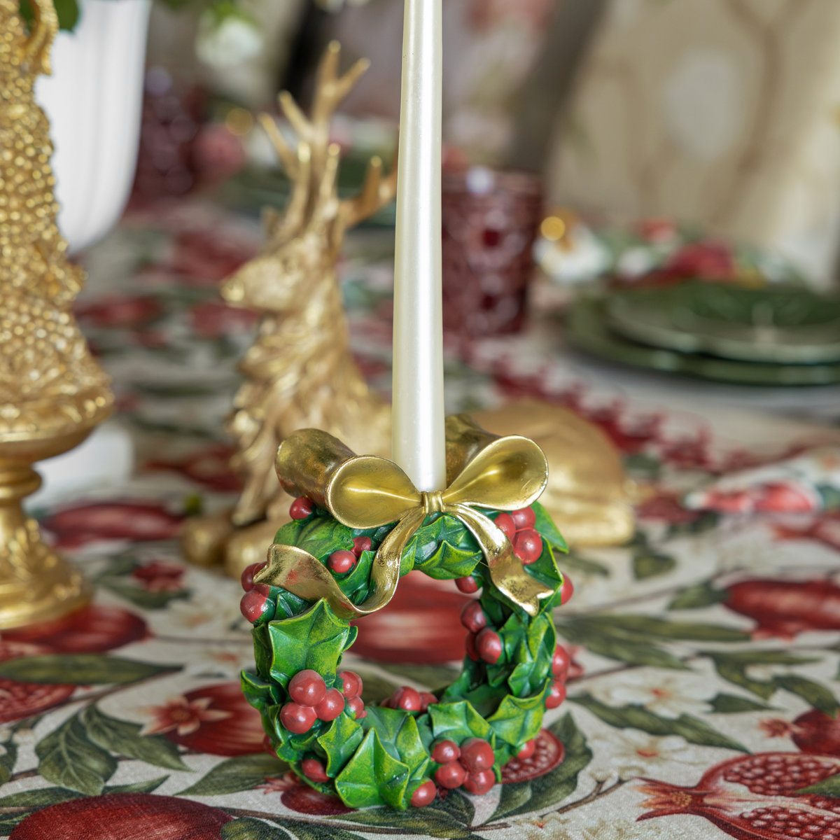 Pomegranate Christmas table styled with holly wreath candle holders and gold resting reindeer