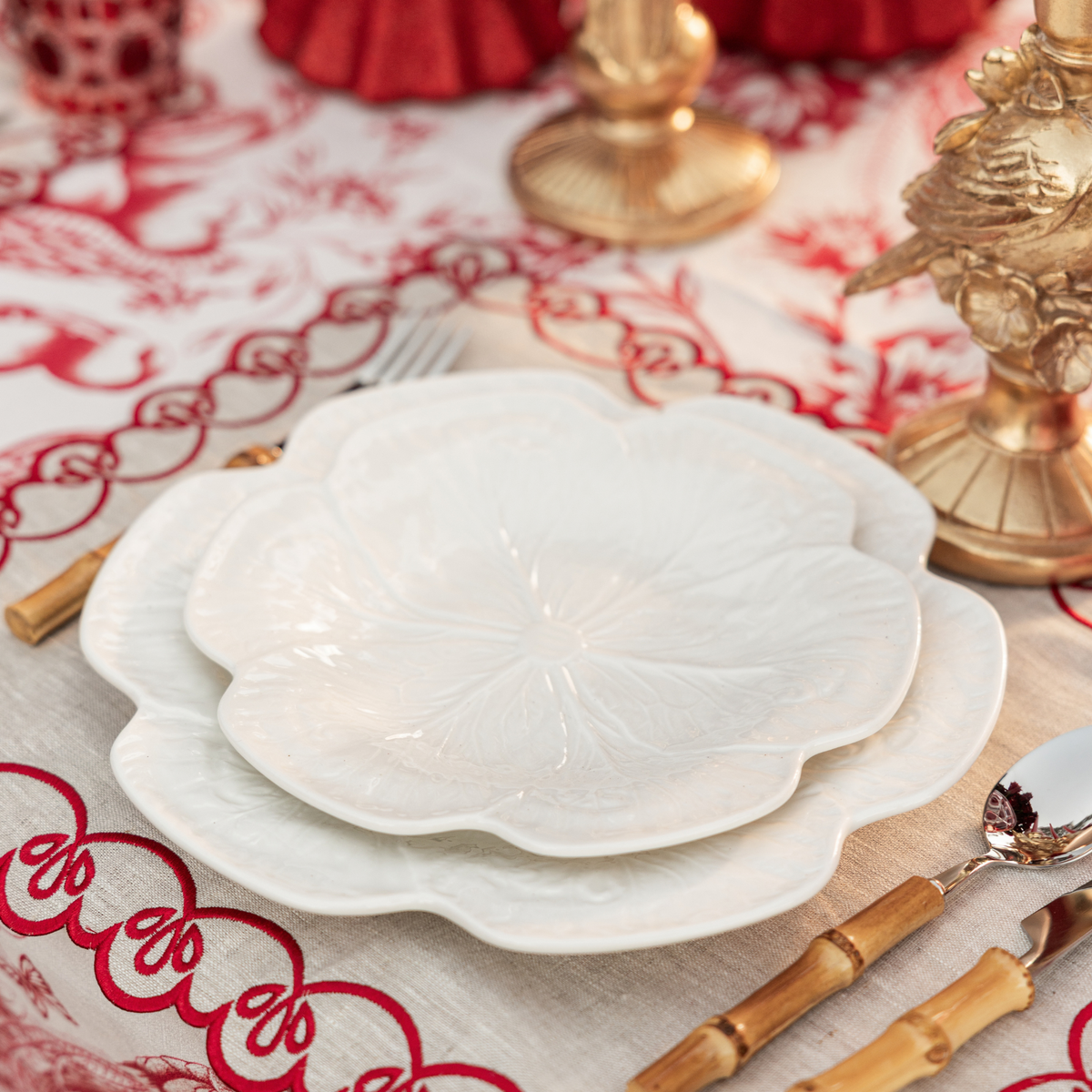 Red Toile Christmas table styled with white cabbage plates and natural linen placemats with red embroidery