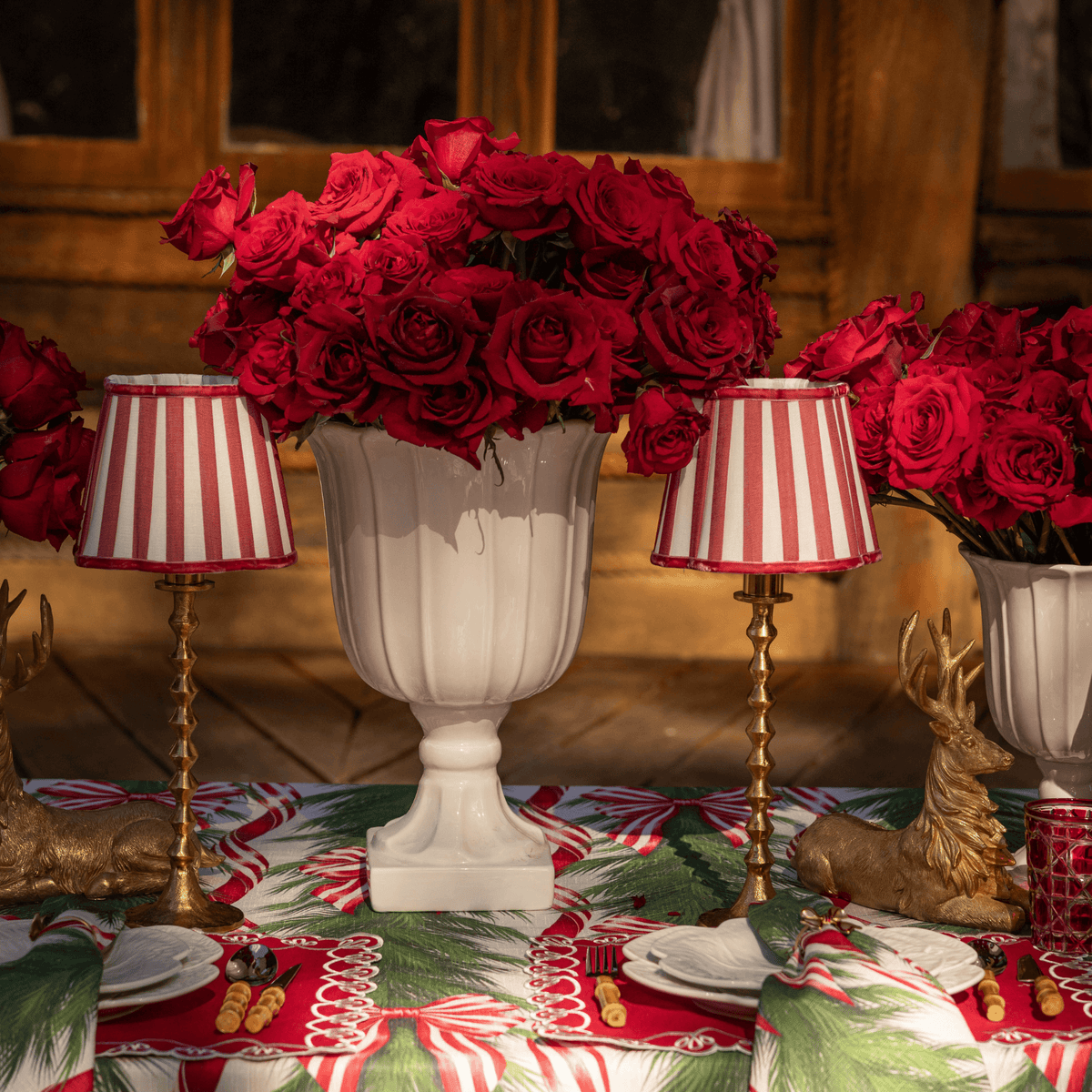 Spruce and Red Bow Christmas table styled with red stripe lamp shade, gold hammered lamp base and gold resting reindeer