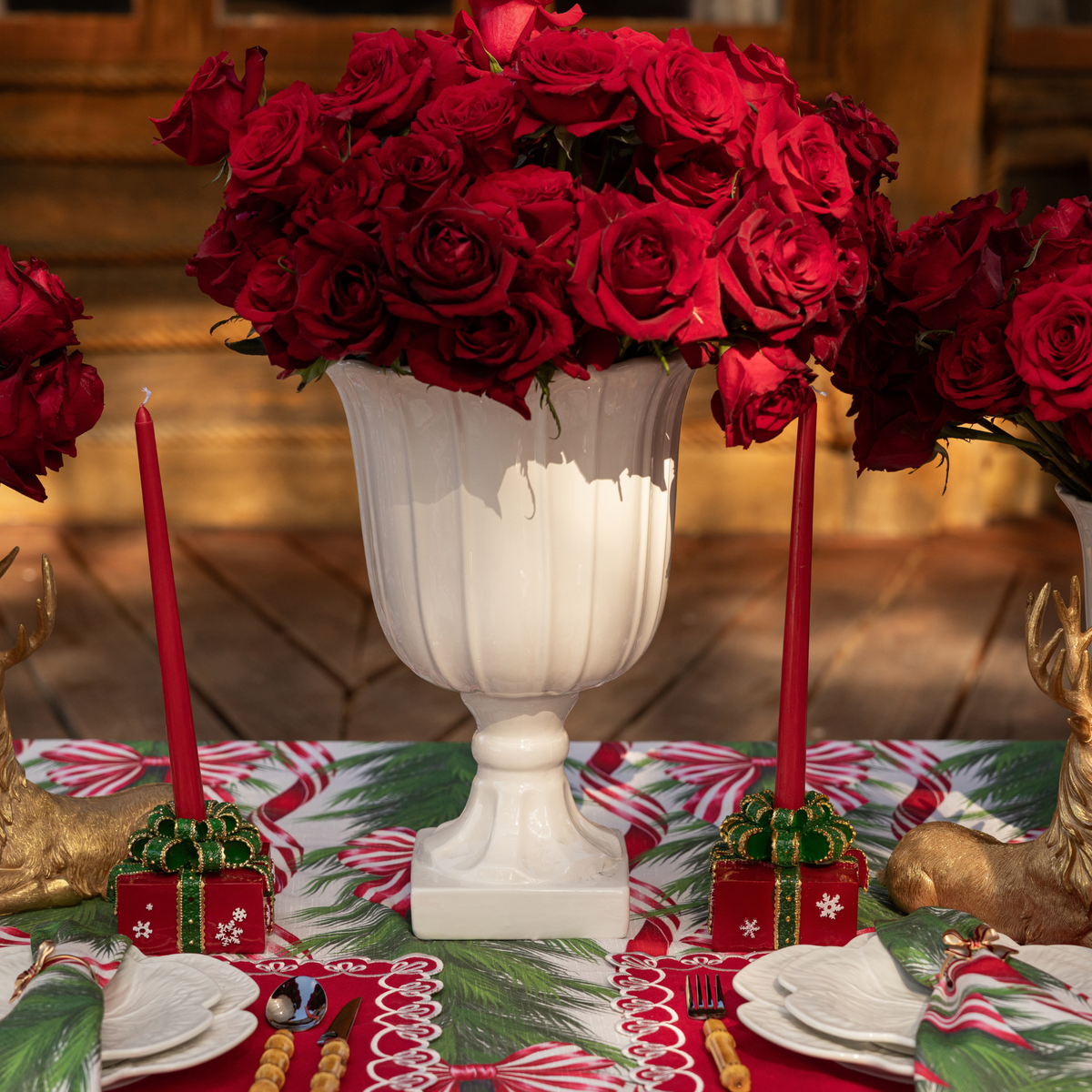 Spruce and Red Bow Christmas table styled with red Christmas present candle holders and gold resting reindeer