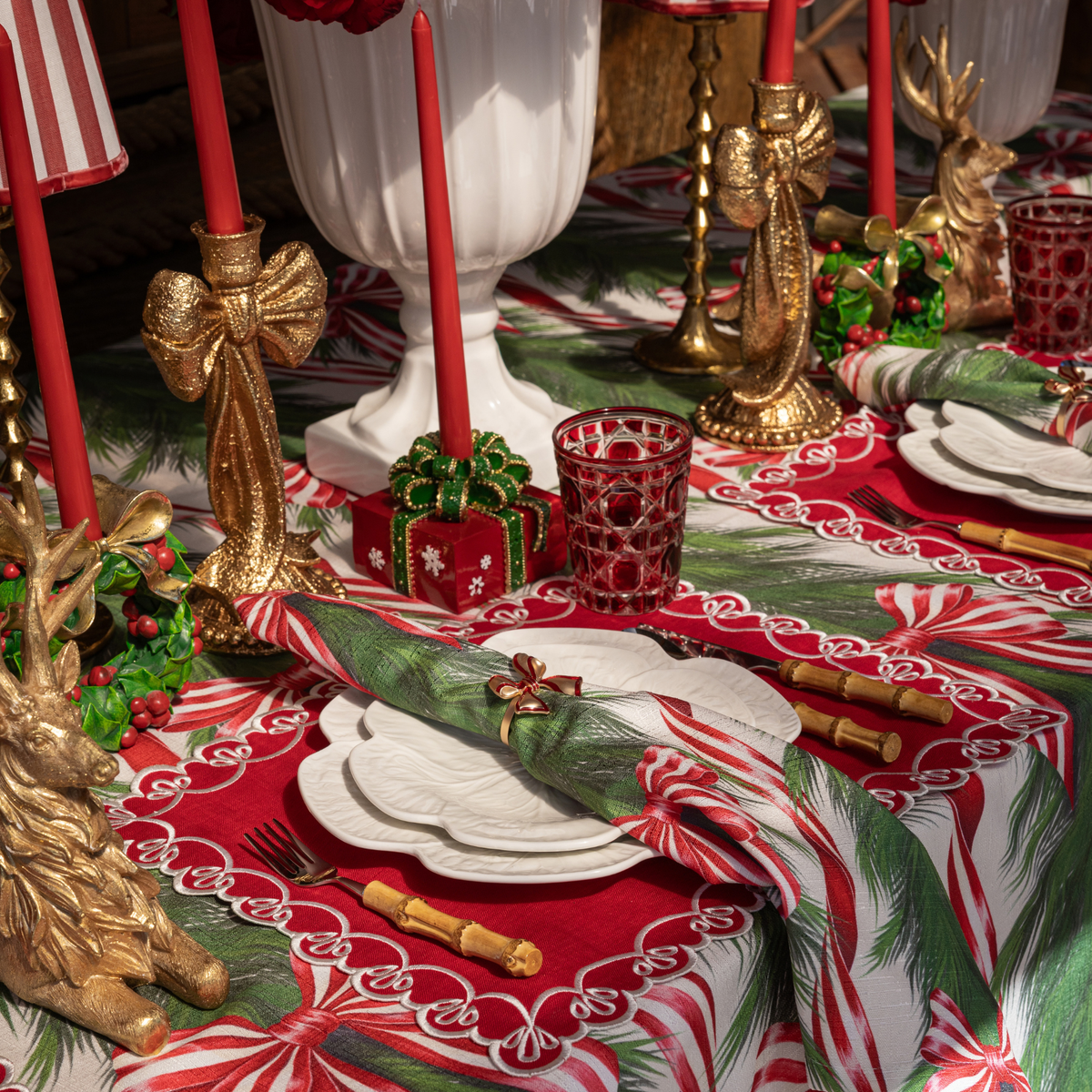 Spruce and Red Bow Christmas table styled with gold bow candle holders and red Christmas present candle holders
