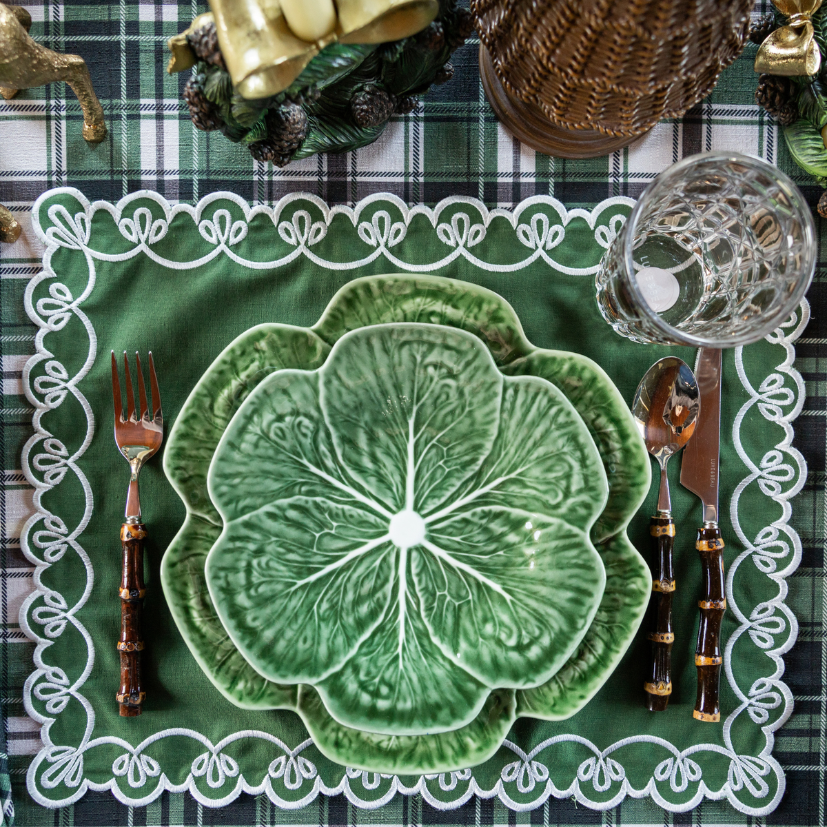 Green and Black Plaid Christmas table styled with green cabbage plates and green placemats with ivory embroidery