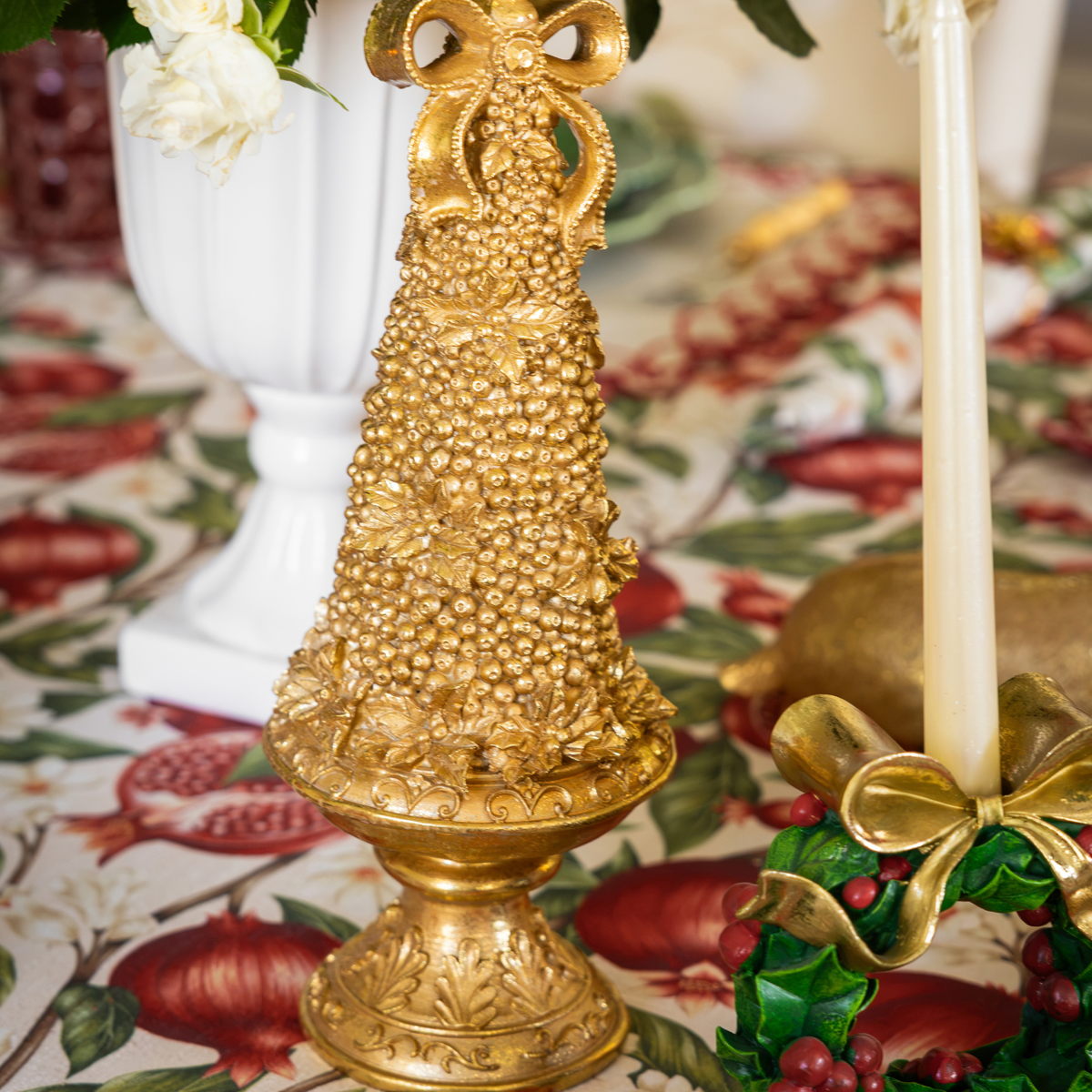 Pomegranate Christmas table styled with gold Christmas tree and holly wreath candle holders