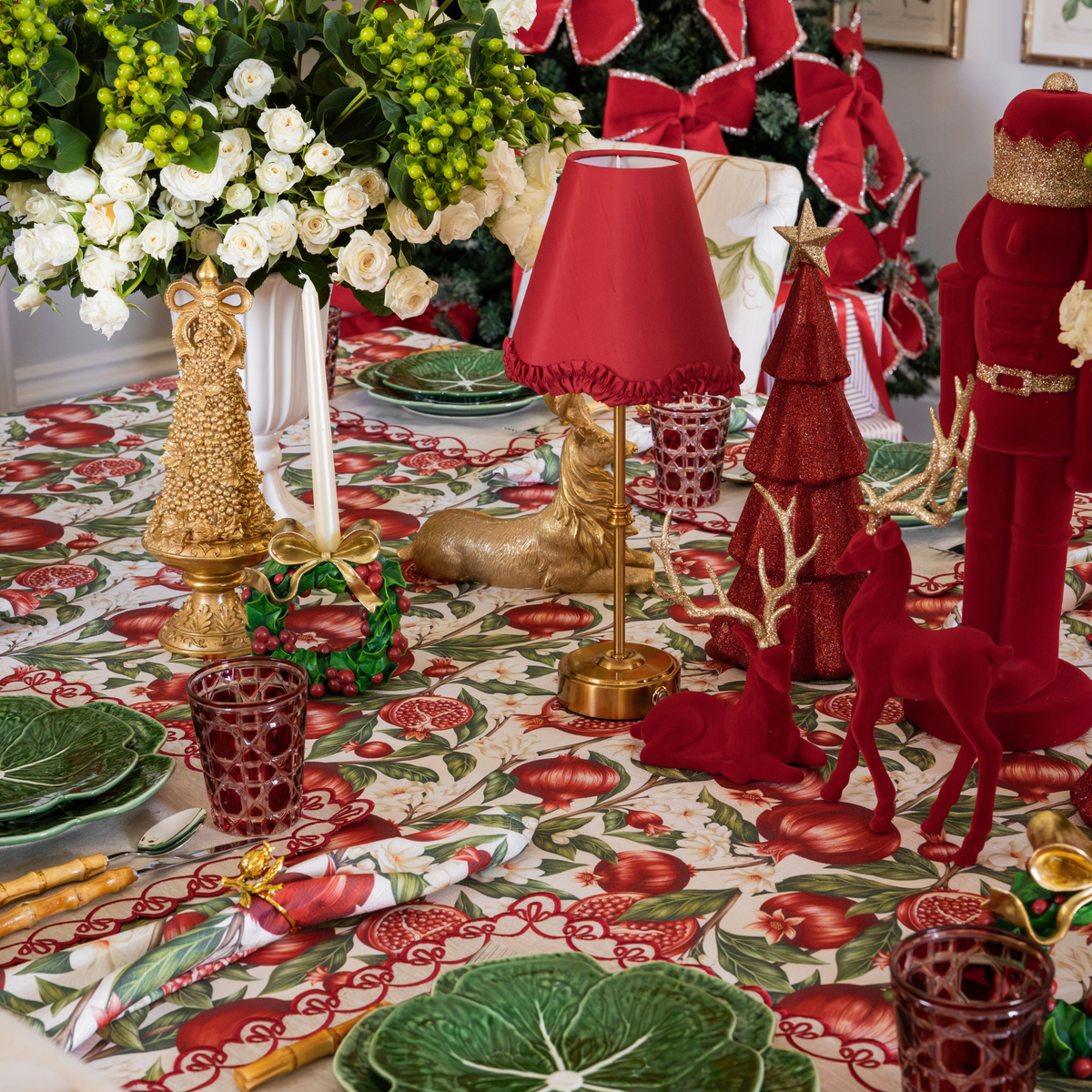 Pomegranate Christmas table styled with burgundy velvet nutcracker, burgundy velvet reindeer and red ruffle lamp shade