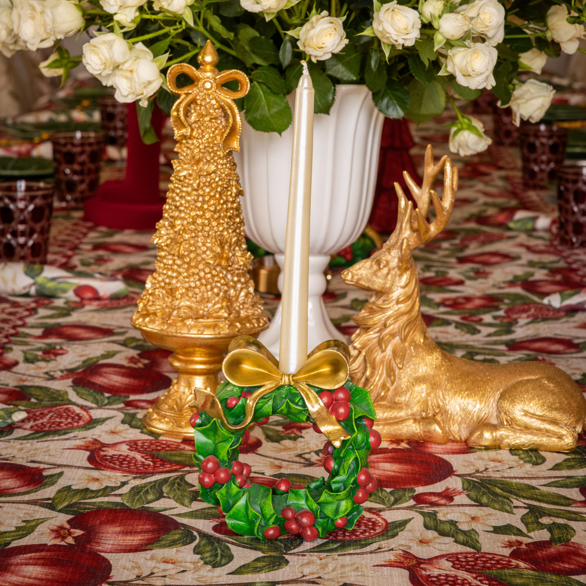 Pomegranate Christmas table styled with gold Christmas tree, holly wreath candle holders and gold resting reindeer