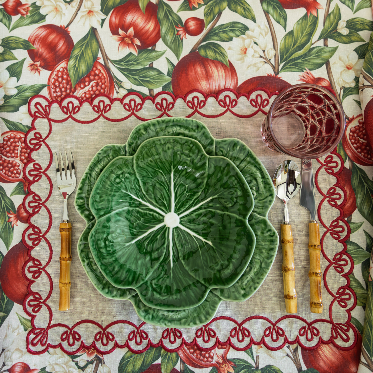 Pomegranate Christmas table styled with green cabbage plates, natural linen placemats with red embroidery and Pomegranate table cloth