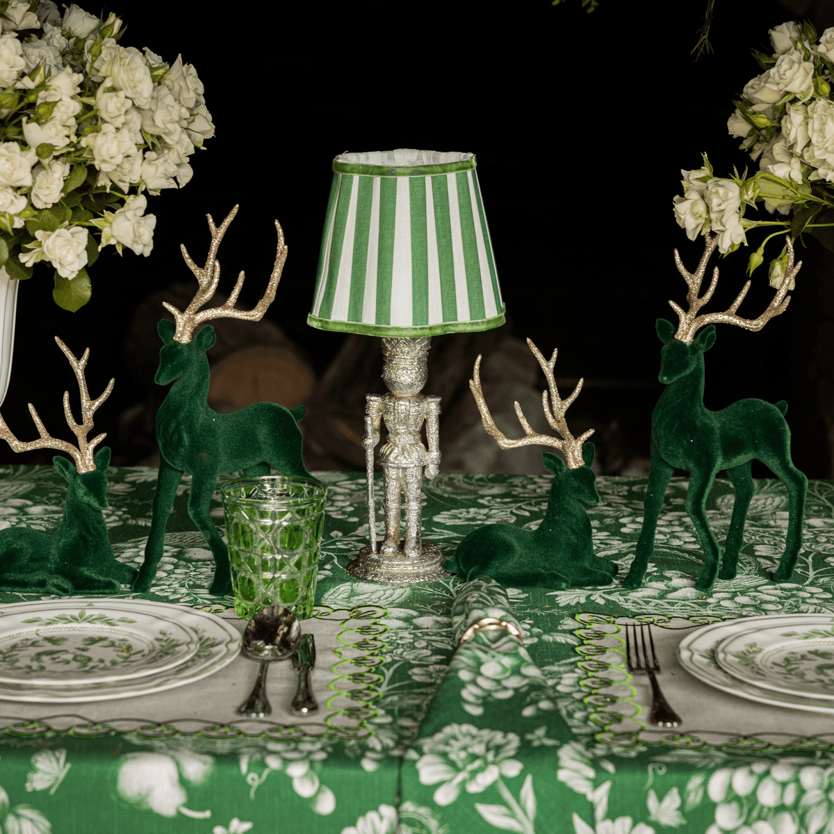 Green Toile Christmas table styled with silver nutcracker lamp, green stripe lamp shade and dark green velvet reindeer