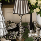 Spruce and Black Bow Christmas table styled with silver hammered lamp base, black stripe lamp shade and silver glitter Christmas trees