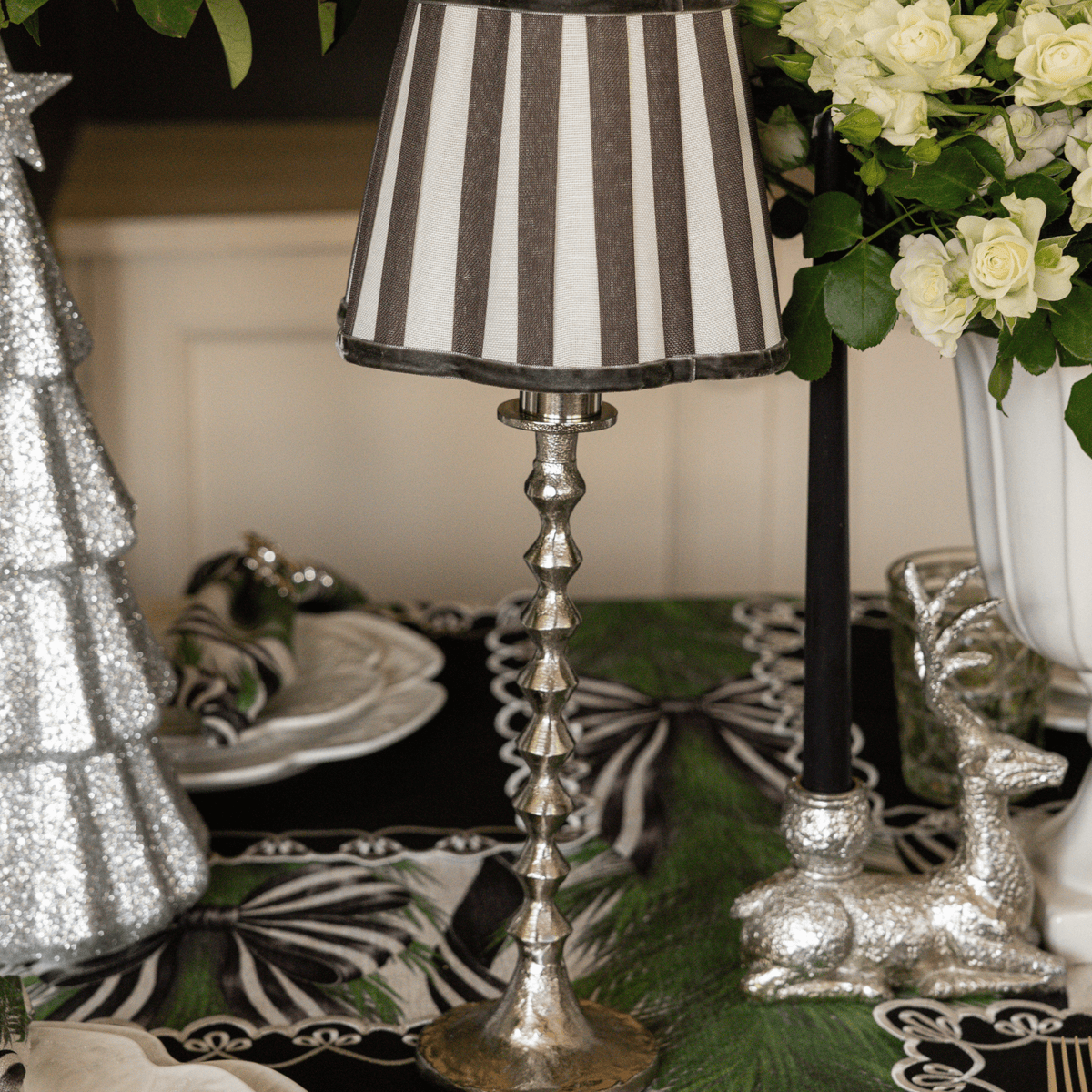 Spruce and Black Bow Christmas table styled with silver hammered lamp base, black stripe lamp shade and silver glitter Christmas trees