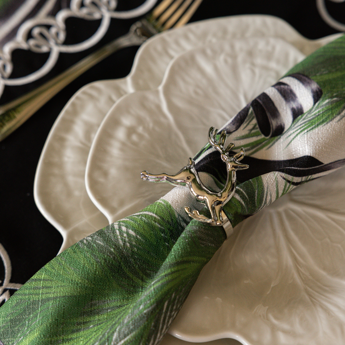 Spruce and Black Bow Christmas table styled with silver deer napkin rings, Spruce and Black Bow napkins and white cabbage plates