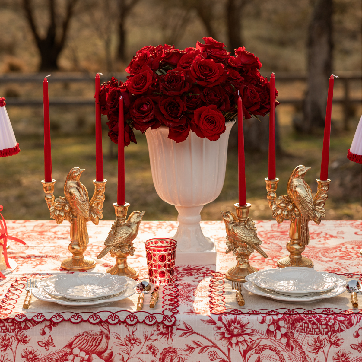 Red Toile Christmas table styled with gold bird double candle holder, gold bird candle holders and red taper candles