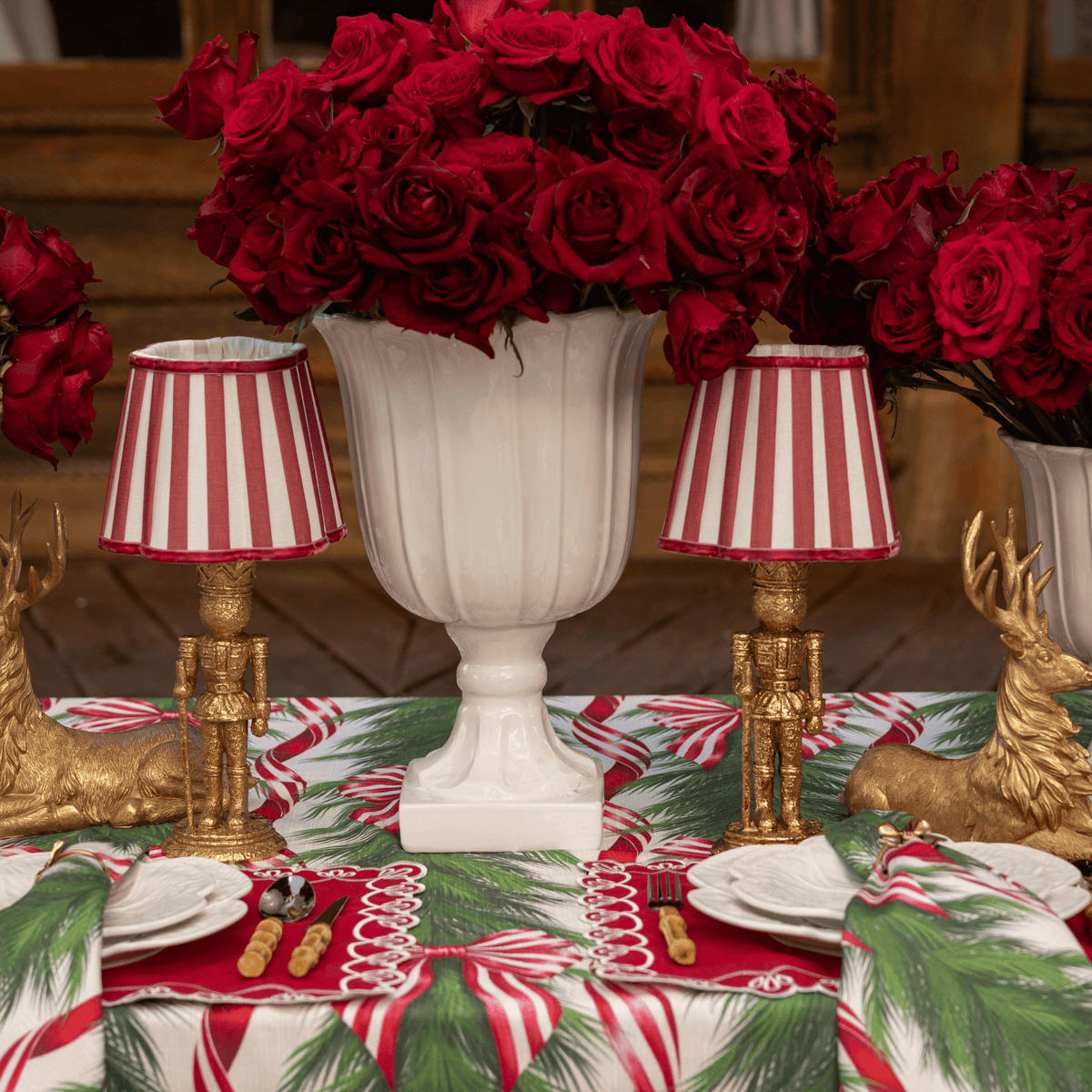 Spruce and Red Bow Christmas table styled with red stripe lamp shade, gold nutcracker lamp and gold resting reindeer
