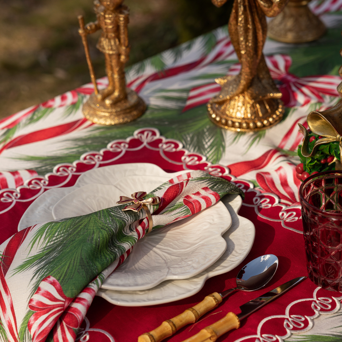 Spruce and Red Bow Christmas table styled with Spruce and Red Bow napkins, red enamel bow napkin rings and white cabbage plates