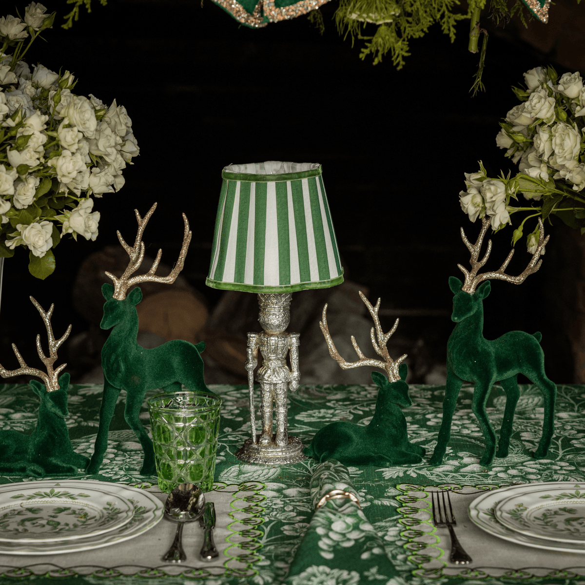 Green Toile Christmas table styled with silver nutcracker lamp, green stripe lamp shade and dark green velvet reindeer