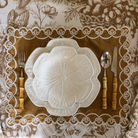 Gold Toile Christmas table styled with gold placemats with ivory embroidery and white cabbage plates