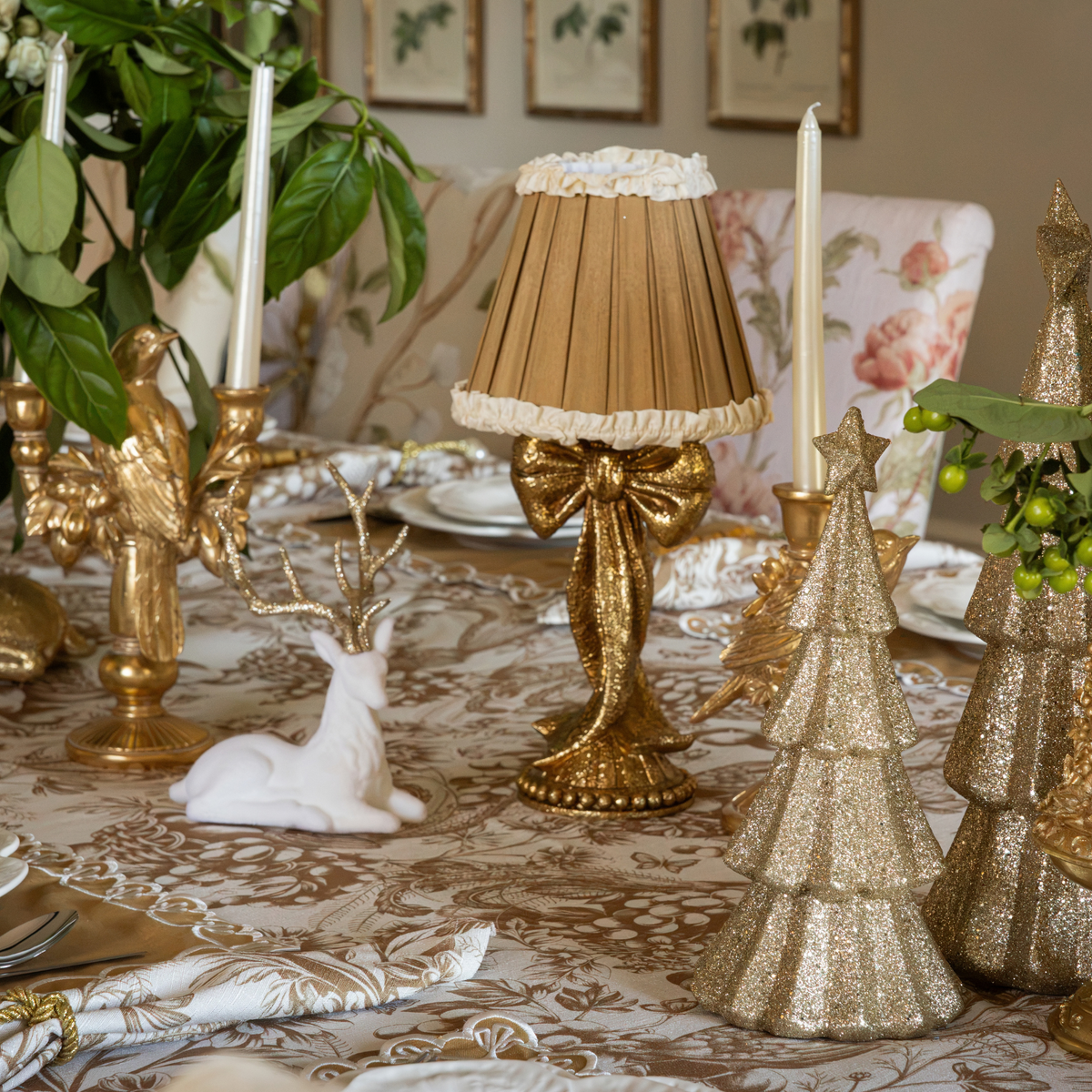Gold Toile Christmas table styled with gold bow lamp, Audrey camel and cream shade and cream velvet reindeer
