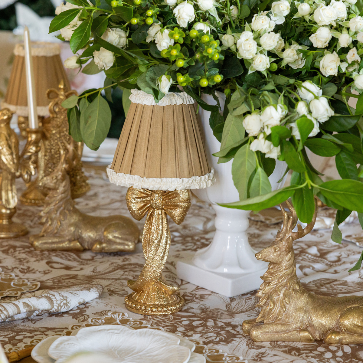 Gold Toile Christmas table styled with gold bow lamp, Audrey camel and cream shade and gold resting reindeer
