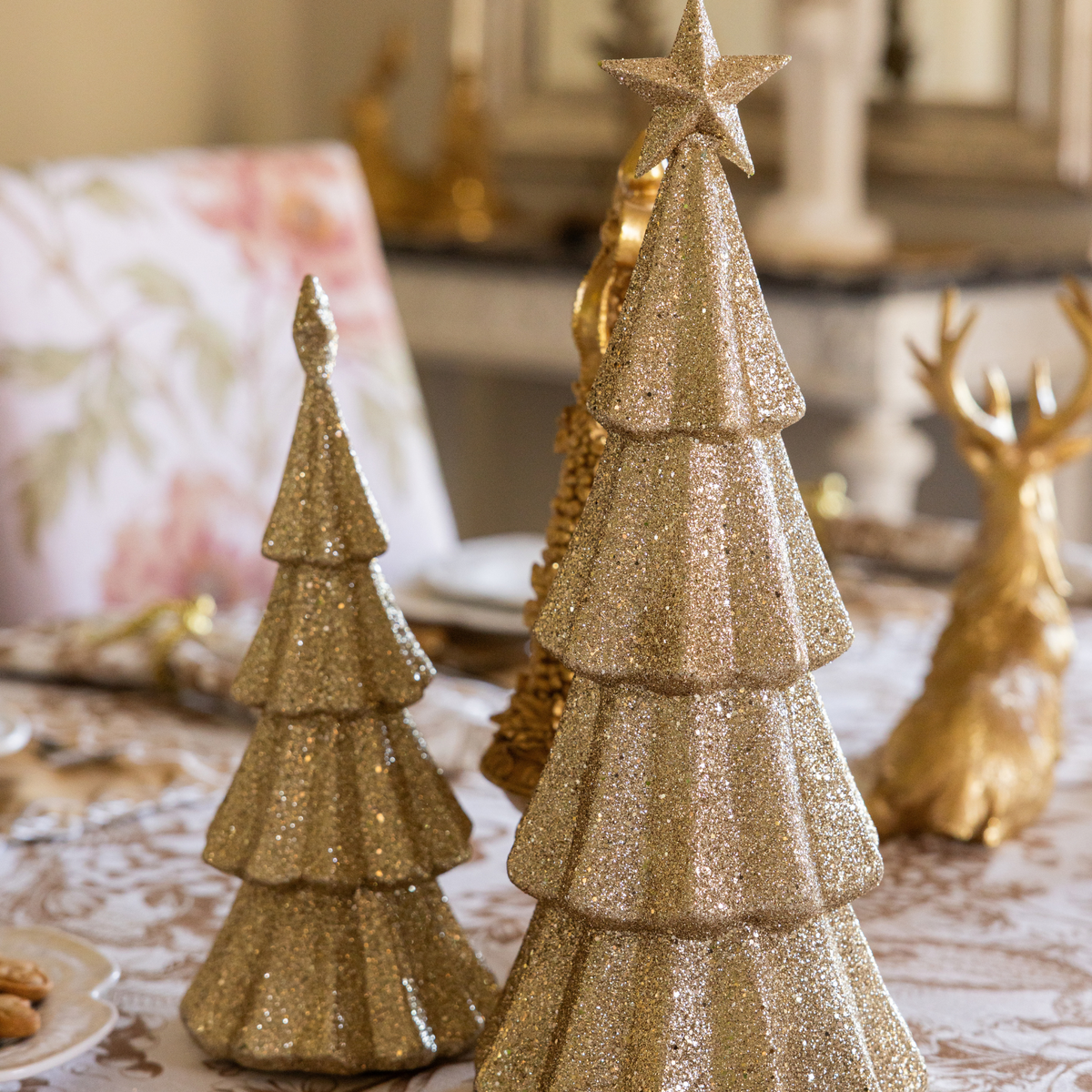 Gold Toile Christmas table styled with champagne glitter Christmas trees and gold resting reindeer